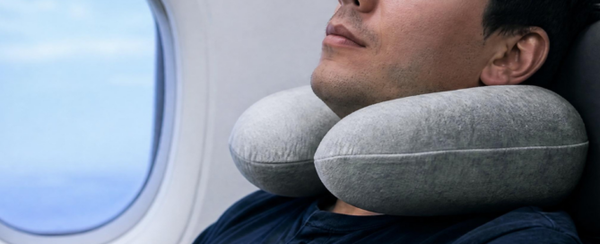 Uomo che riposa in aereo con un cuscino da viaggio, immagine dedicata ai consigli per prevenire e gestire il jet lag.