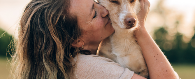 Ragazza che abbraccia e bacia il proprio cane, immagine dedicata alla Giornata Mondiale del Cane e alla cura del suo benessere.