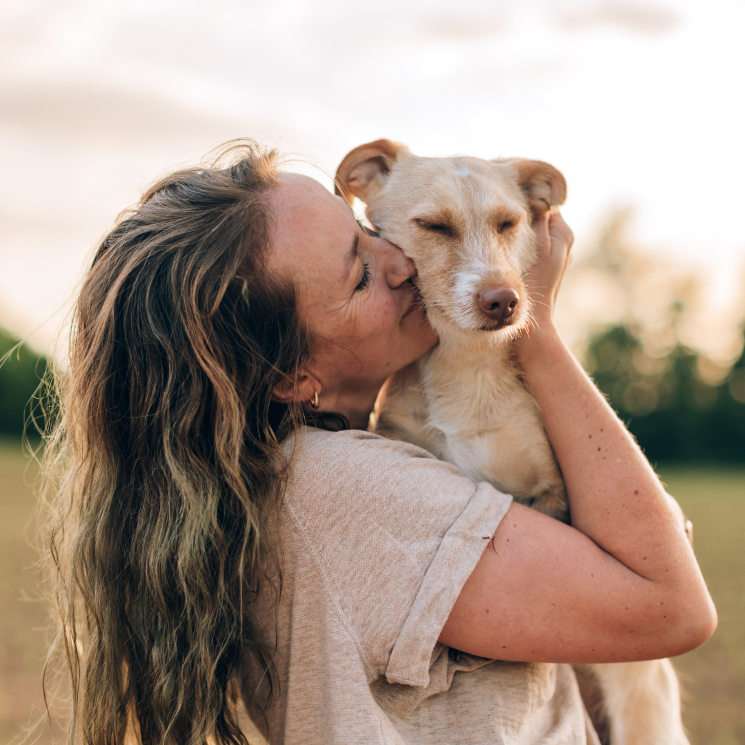 Ragazza che abbraccia e bacia il proprio cane, immagine dedicata alla Giornata Mondiale del Cane e alla cura del suo benessere.