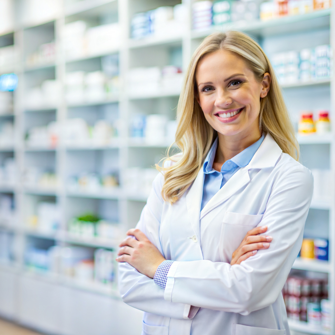 Farmacista sorridente in camice bianco all'interno di una farmacia, in occasione della Giornata mondiale del Farmacista